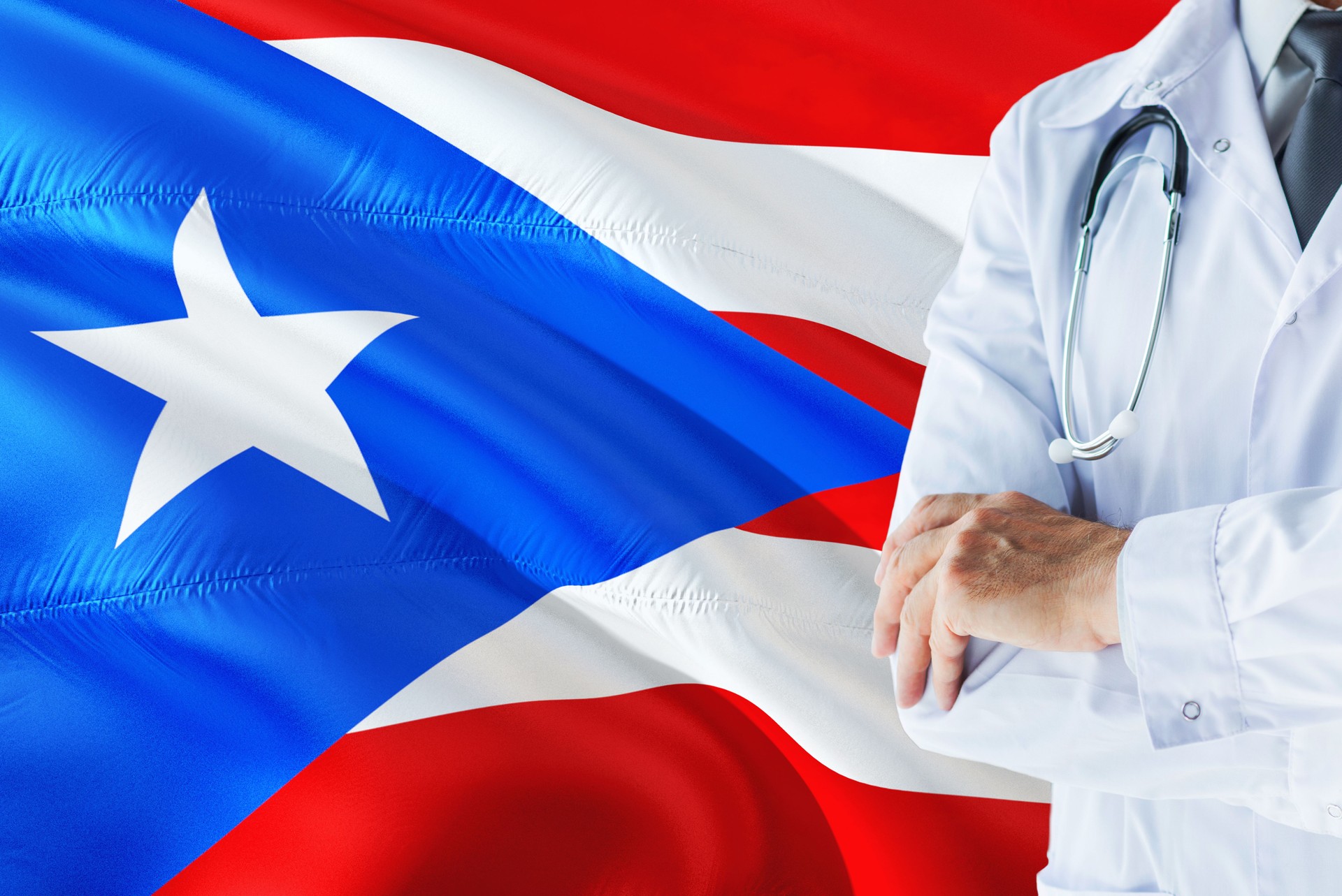 El doctor de pie con estetoscopio sobre fondo de bandera de Puerto Rico. Concepto de sistema nacional de salud, tema médico.